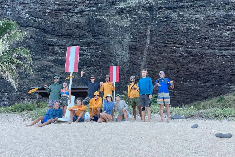 A Na Pali Kayak group on the beach at the foot of the cliffs