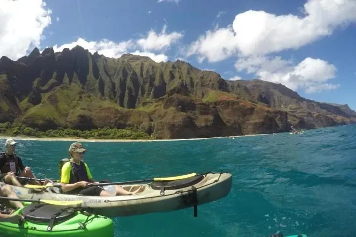 Kayakers paddling below the fluted cliffs of the Na Pali Coast
